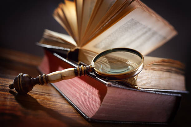 istock Old book and magnifying glass 506784394