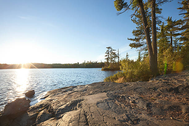 Sunset on lake with rocky shore in northern Minnesota Sunset on lake with rocky shore in northern Minnesota boundary waters canoe area stock pictures, royalty-free photos & images