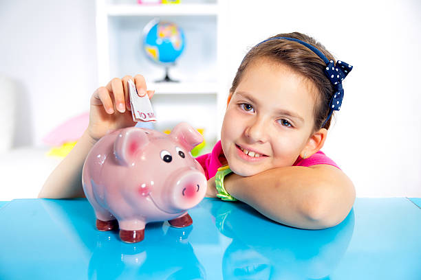 menina colocar um piggybank papel-moeda no seu - greenbacks imagens e fotografias de stock