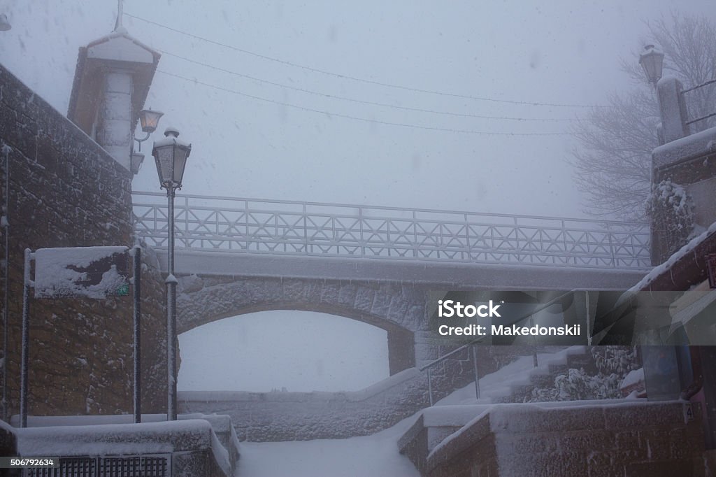 Stone Bridge in a snowstorm. Beautiful view of the stone bridge in the old town in a snowstorm. Arch - Architectural Feature Stock Photo