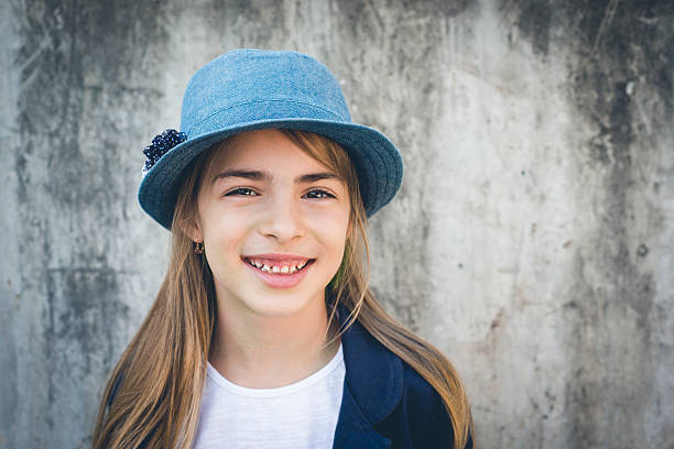 Cute little girl with a blue hat smiling and looking at the camera. Horizontal framing.