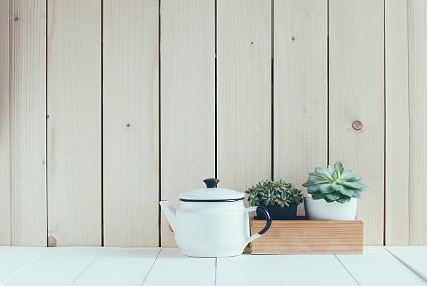 A delicate white ceramic teapot stands on a white table setting