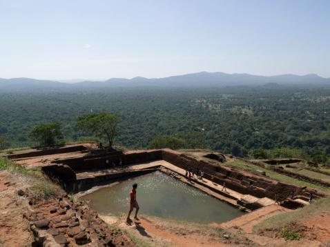 Sigiriya, Sri Lanka - October 8, 2013: The 5th Century Rock Fortress, which was established by King Kassapa who reigned between 473 and 491 AD. This image shows tourists at the ruins of the original Royal swimming pool with views over the surrounding countryside.