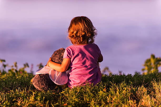 Lonely little girl on riverbank