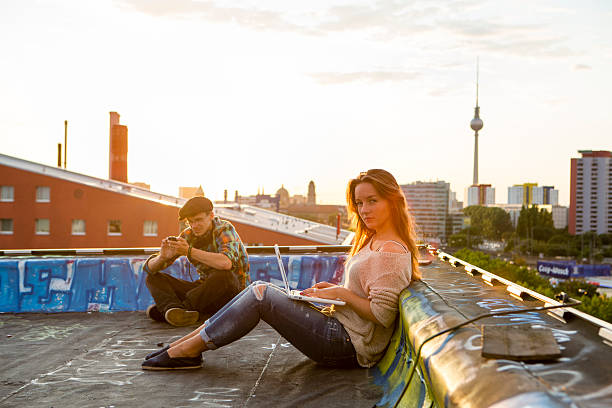 istock Berlin: young adults sitting on a roof, back lit 506798757