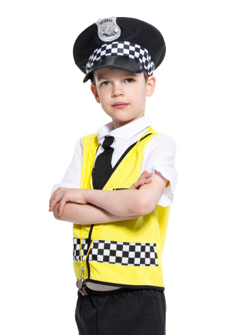 Portrait of little boy dressed as a policeman, standing with arms crossed and looking at camera. Studio shot, isolated on white.