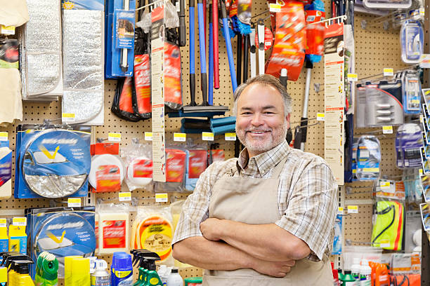 Happy Hardware Store Salesperson Portrait of a happy mature salesperson with arms crossed in hardware store hardware store photos stock pictures, royalty-free photos & images