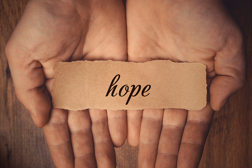 Hands holding piece of paper with word Hope