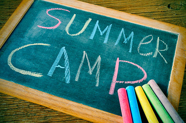 summer camp text summer camp written with chalk on a chalkboard, and some chalk sticks of different colors summer camp photos stock pictures, royalty-free photos & images