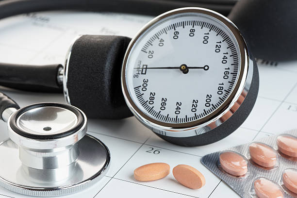 Tablets and Blood Pressure Meter on a Calendar Statins or generic medicines on a calendar with a sphygmanometer and stethoscope. Medical check up concept. blood pressure medication stock pictures, royalty-free photos & images