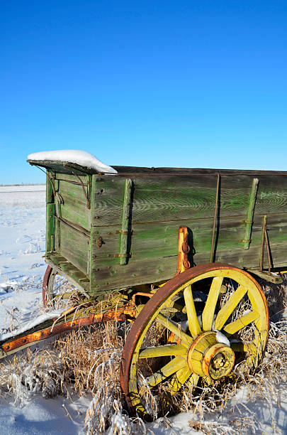 Snow Covered Wagon An image of an old wooden wagon in snow against a clear blue sky. covered wagon horse cart snow winter stock pictures, royalty-free photos & images
