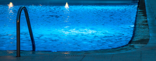 Above view of large group of carefree people having fun during the night in the swimming pool.
