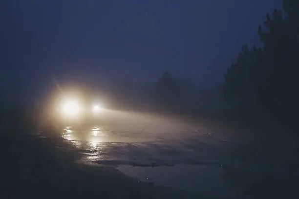 Car on dirty road in strong haze fog at twilight