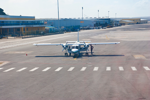 Willemstad, Curaçao, April 1, 2014: Curaçao International Airport, a small aircraft a BN-2 Islander on taxiway getting checked by two aircraft technicians and the pilot for the next depature.