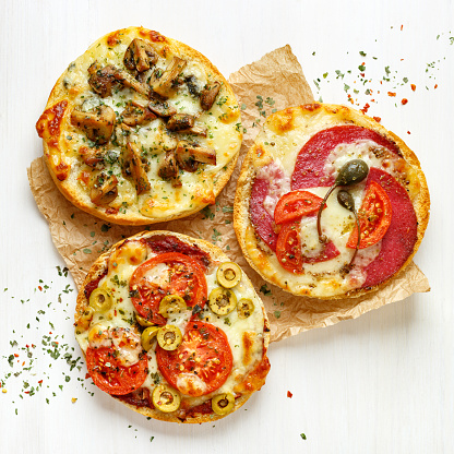 Grilled sandwiches with cheese, tomatoes, salami, mushrooms and olives on a white background
