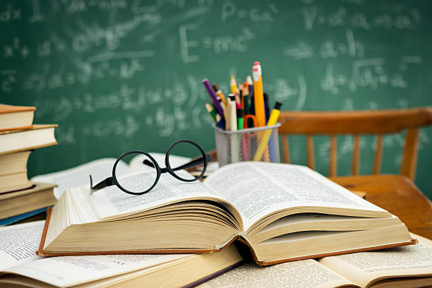 istock Desk full of open books over blackboard 506821268
