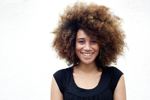 Portrait of young african american woman smiling with afro against white background