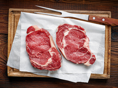 fresh raw beef steak on wooden cutting board, top view