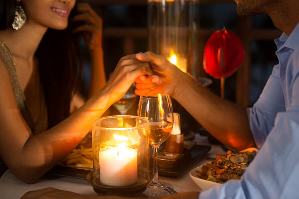 Romantic couple holding hands together over candlelight Romantic couple holding hands together over candlelight during romantic dinner candle light dinner stock pictures, royalty-free photos & images