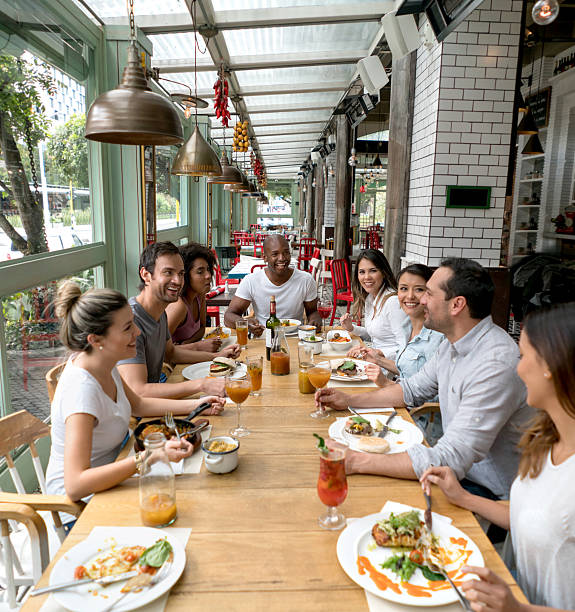 Happy group of people eating together at a restaurant and having fun catching up