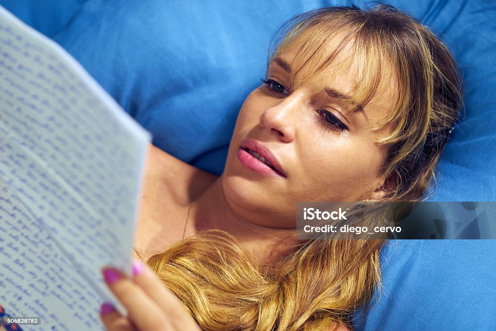 Girl In Bed Crying With Love Letter From Boyfriend Young caucasian teenager receiving love letter from her boyfriend. The girl lays on bed and cries reading bad news. 20-29 Years Stock Photo