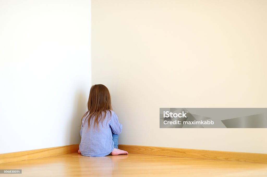 Sad little girl sitting in a corner Very sad little girl sitting on a floor at home Child Stock Photo