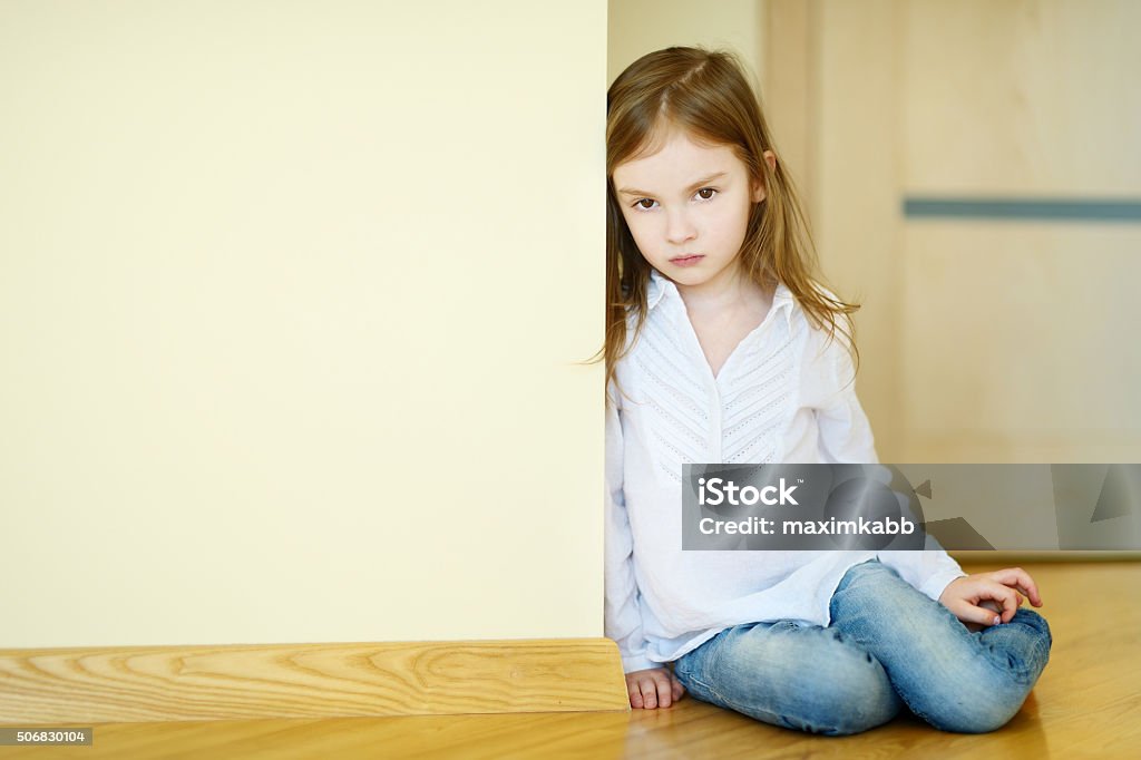 Sad little girl sitting on a floor Sad little girl sitting on a floor at home Anger Stock Photo