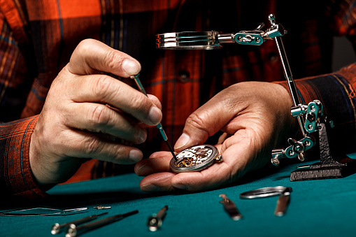 Pocket watch being repaired by senior watch maker, close-up.