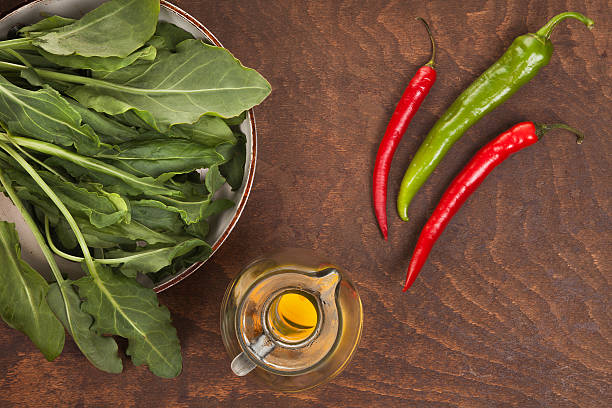 pepper, olive oil and green leaves on a dark wood table