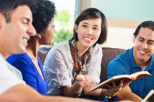 Young Asian woman leading Bible study group at home