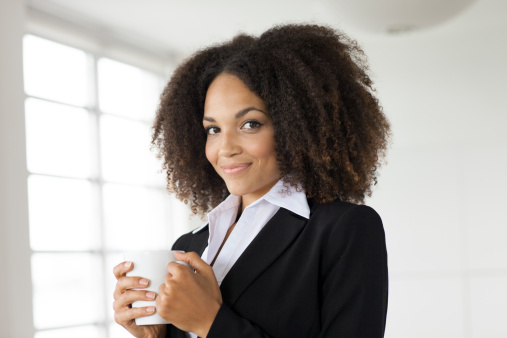 close up of young business woman holding cup of coffee.