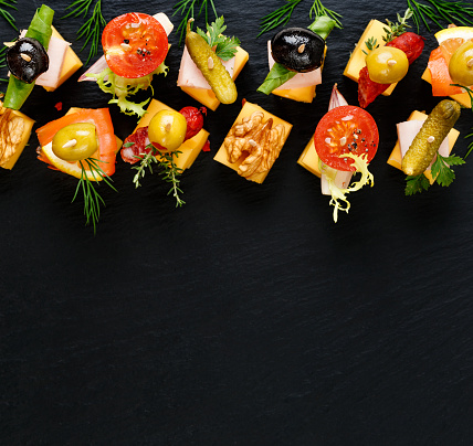 Delicios appetizers with cheese and variety ingredients on a black background