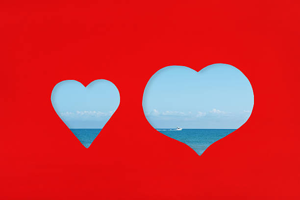 Hearts shaped cut on red paper with sea view through.Love and vacation concept.