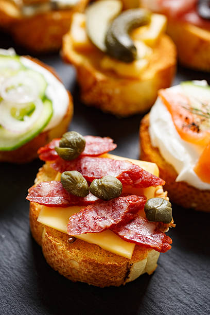 istock Small canape with grilled baguette, cheese, sausage and capers 506850198