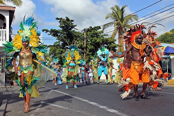 Marigot Carnival 2015 - 8 Marigot, Saint Martin (French part) - February 17th, 2015: Participants on parade in Rue Low Town, Marigot during the Marigot Carnival or "Carnaval de Marigot" (an annual event / celebration in Saint-Martin) walking down the street. They wear brightly colored costumes decorated with flamboyant feathers on the headdresses. The different styles of the costumes indicate which troupe the performers belong to. saint martin caribbean stock pictures, royalty-free photos & images