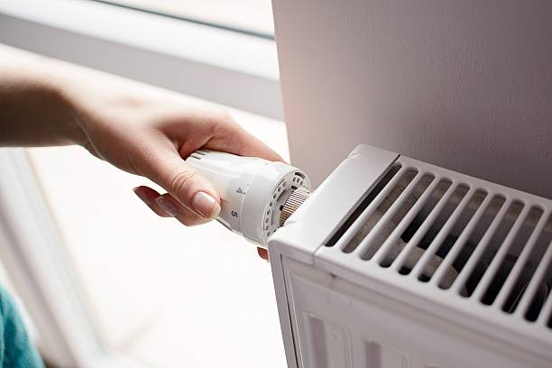 Hand adjusting thermostat valve Closeup on woman's hand adjusting thermostat valve radiator stock pictures, royalty-free photos & images