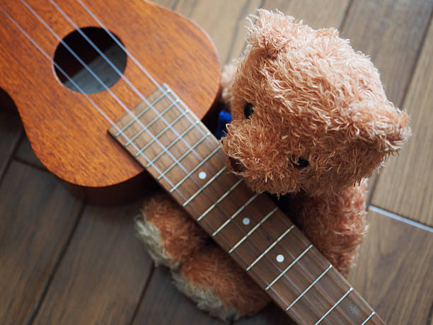 istock Lovely Brown Bear Sitting along with Ukulele 506878508