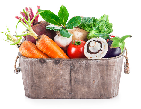 Fresh organic vegetables in wicker basket onwhite background