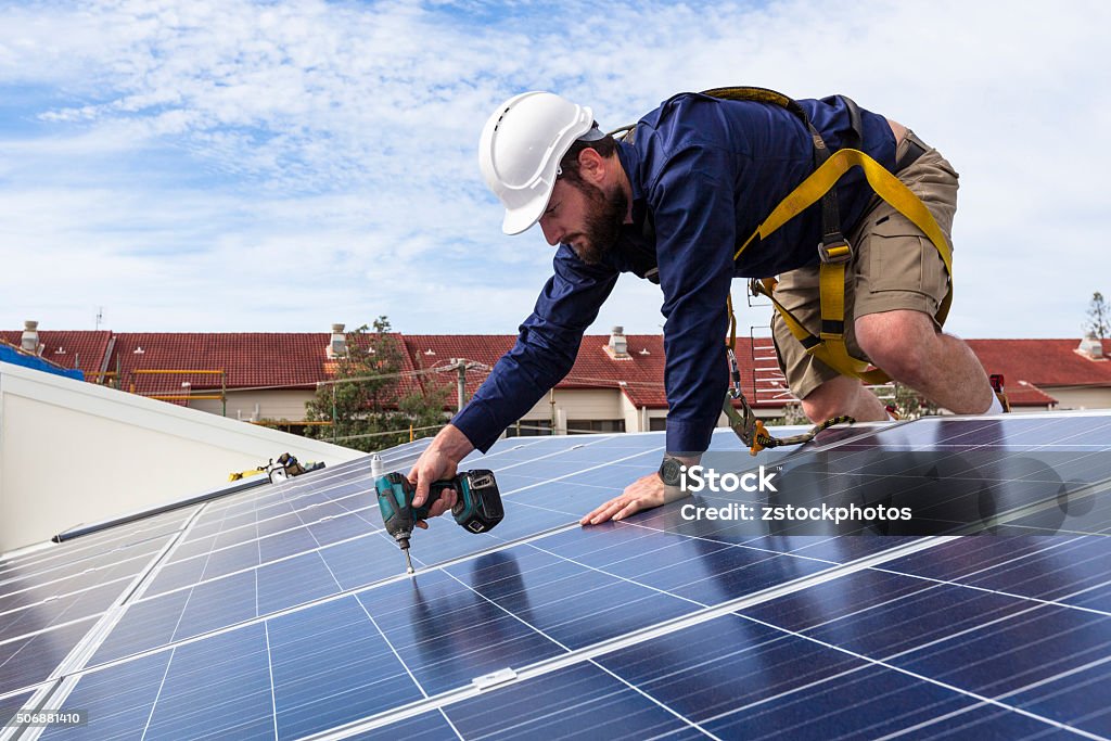 Solar panel technician Solar panel technician with drill installing solar panels on roof Solar Panel Stock Photo
