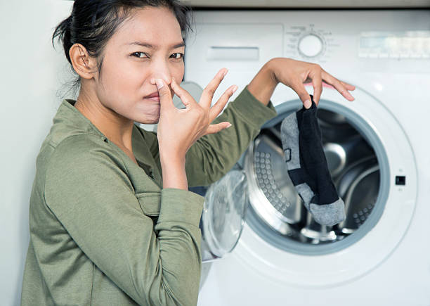 mujer dando una sucio calcetín en una máquina de lavado - human nose smelling scented unpleasant smell fotografías e imágenes de stock