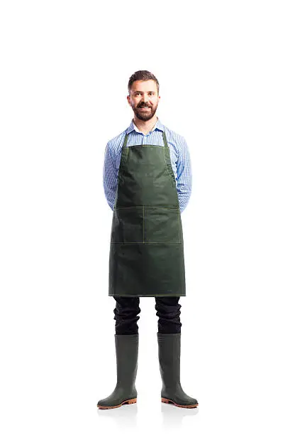 Young handsome gardener in green apron. Studio shot on white background