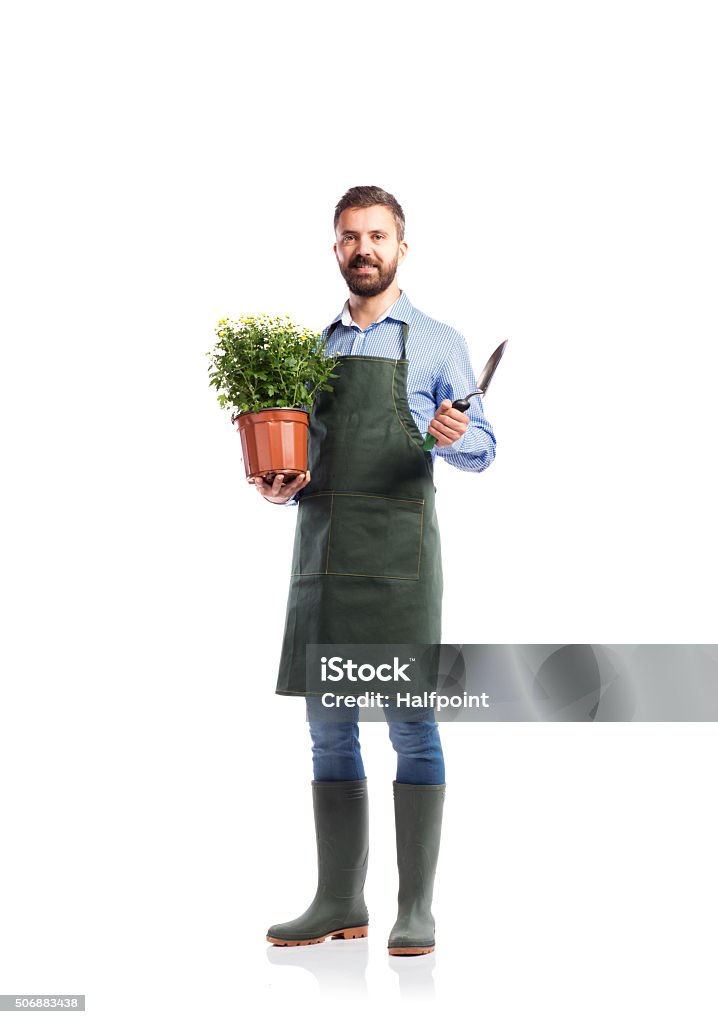 Young handsome gardener Young handsome gardener in green apron. Studio shot on white background Gardening Stock Photo