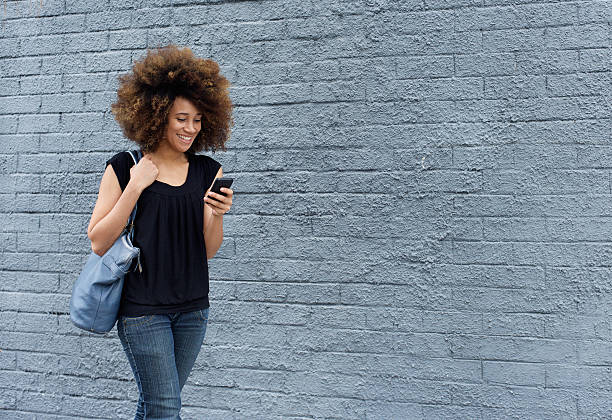 istock Smiling woman walking with cell phone 506884784