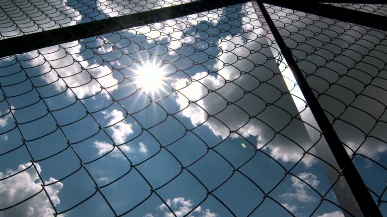 Dolly: Sun shining through the chain link iron wire fencing