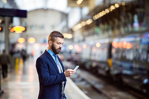 hombre de negocios con teléfono inteligente - subway station railroad station uk passenger fotografías e imágenes de stock