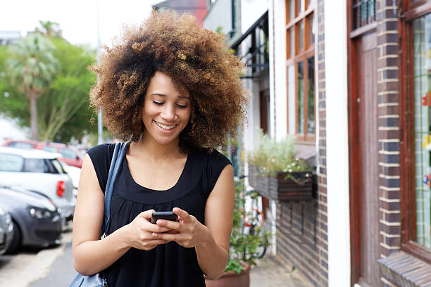 istock Happy black woman walking and reading text message 506891342
