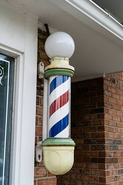 istock An old fashioned barber pole in front of a brick building. 506891567