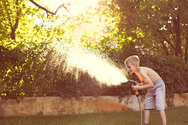 istock Boy playing with water in garden 506891802