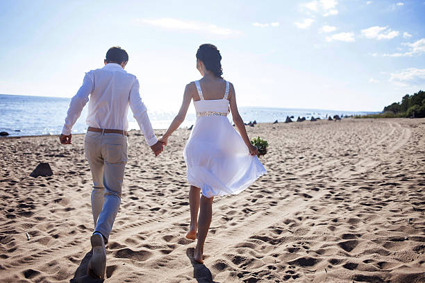 istock Just married happy couple running on a sandy beach, view 506895780