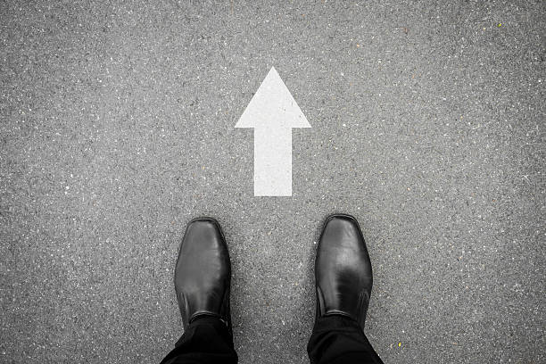 istock Black shoes and direction sign to go ahead 506899138